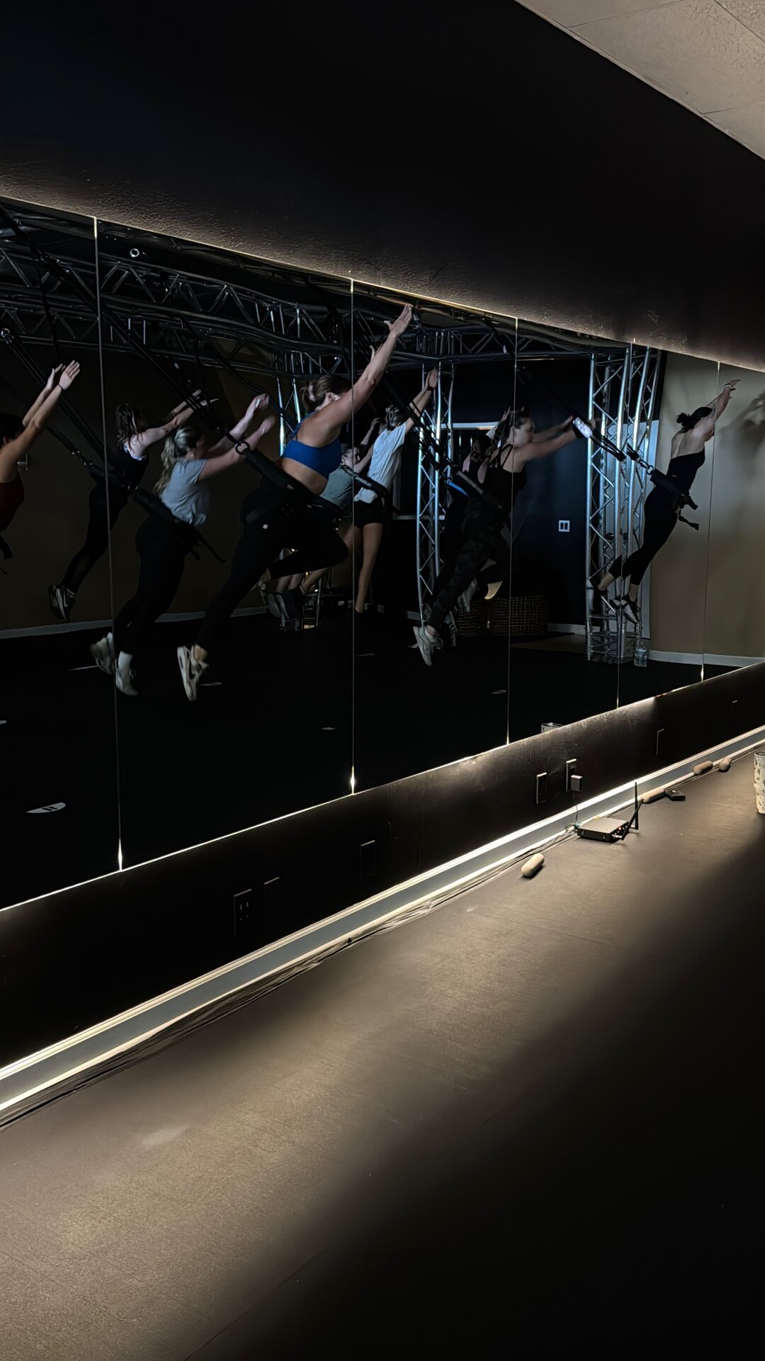 Students mid-flight in superman poses reflected in the studio mirrors during a bungee fitness class in Huntington Beach